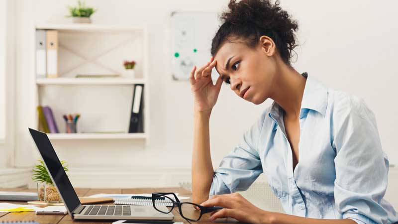 A woman staring at her laptop, confused