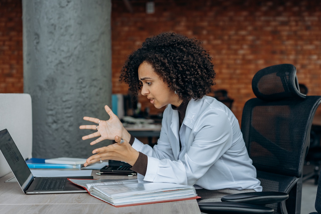 Frustrated woman gesturing to laptop