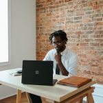 Man looking at his laptop. Screen is hidden from view.
