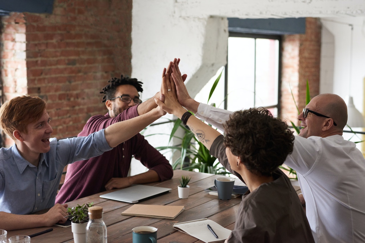 Group of four high-fiving over table