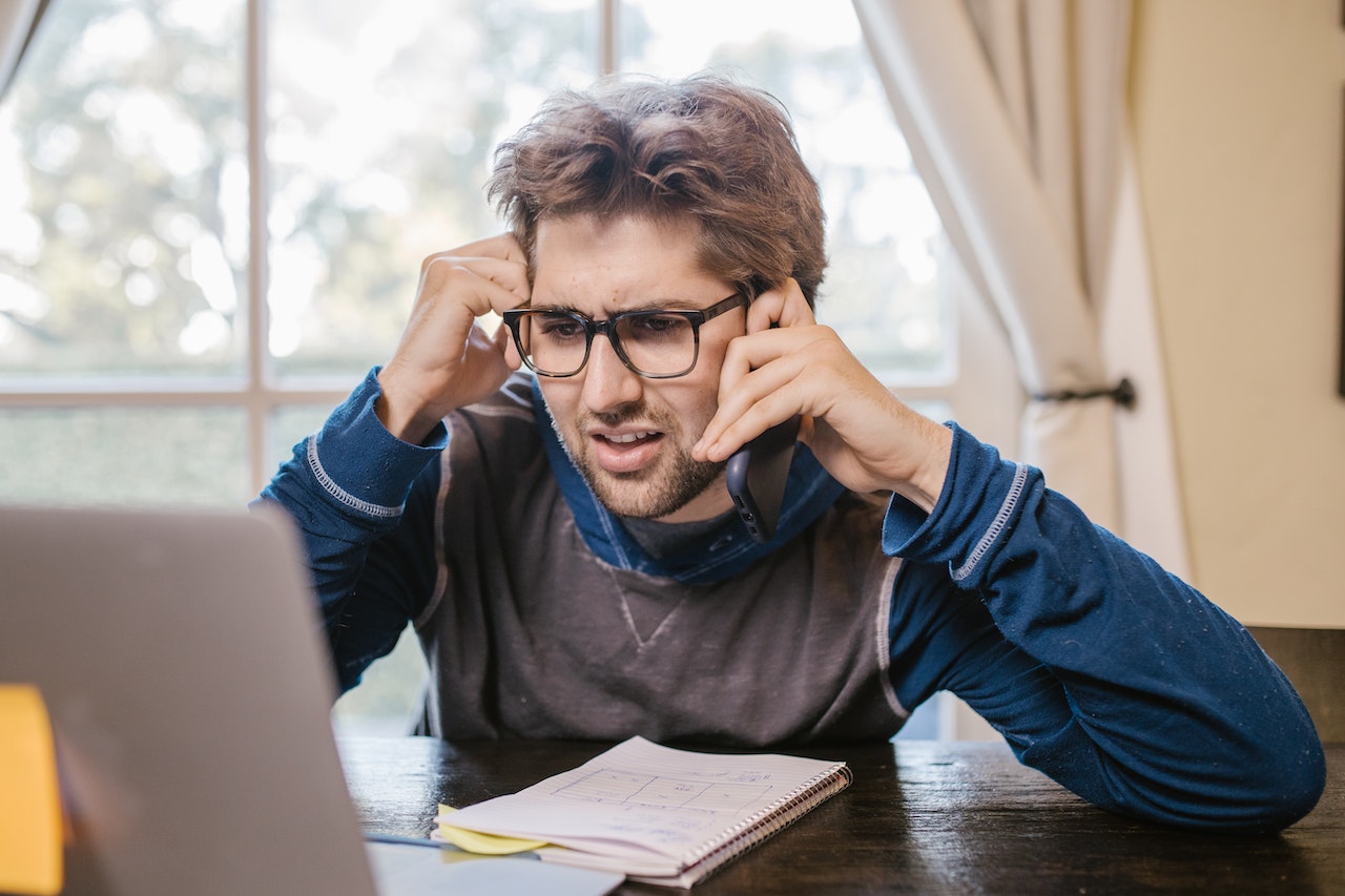 Man confused on the phone, looking at computer