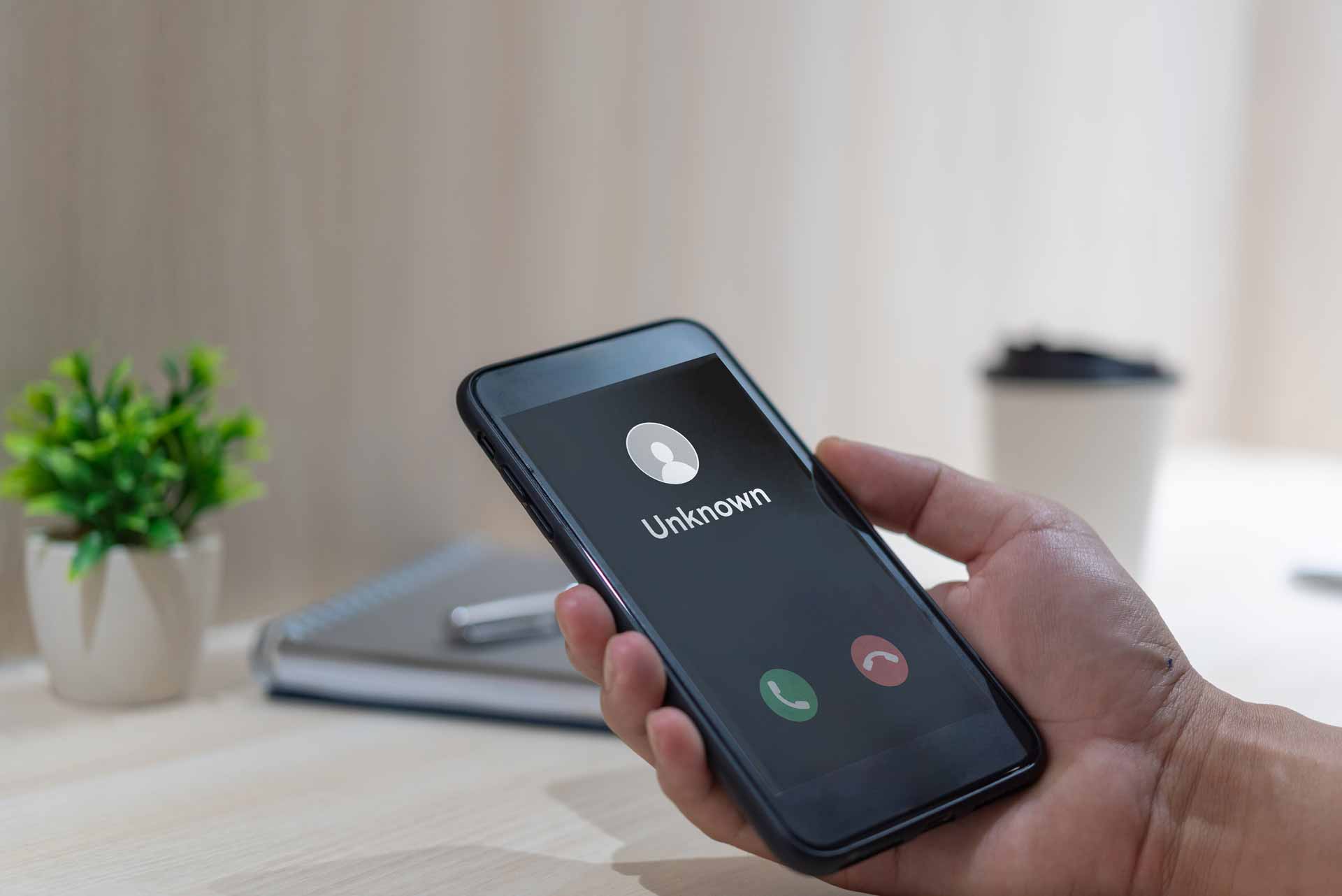 Smartphone in hand, showing incoming call from unknown caller