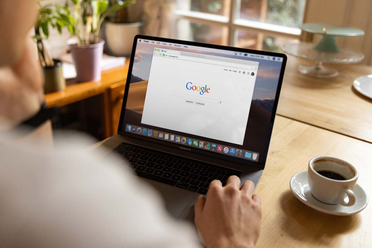 Over-the-shoulder shot of a man using Google on his laptop